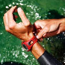 A picture from a bird's eye view angle of someone wearing a watch that is covered with water. The background shows the person must be standing by a body of water.