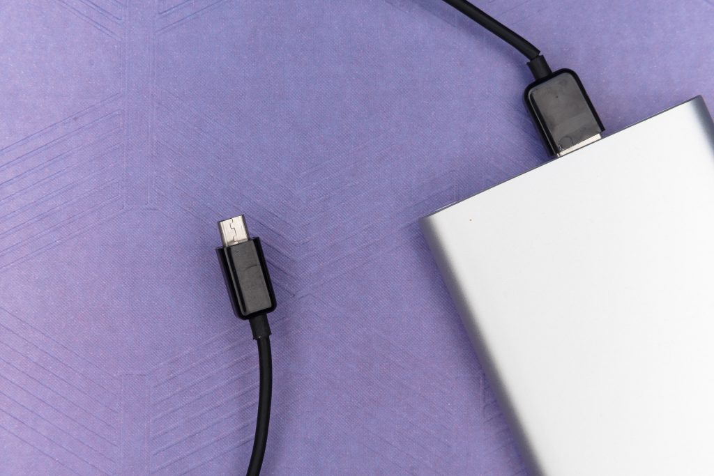 A picture of a power bank that has a black charging cable attached to it.