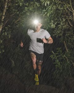 A man running in the forest at night in the rain.